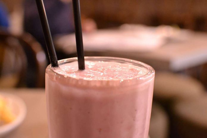Milkshake alle fragole fresco e cremoso in bicchiere alto di vetro