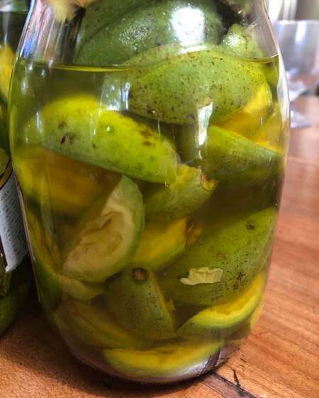 Noci acerbe tagliate, zucchero sciolto e alcool alimentare dentro a vaso di vetro