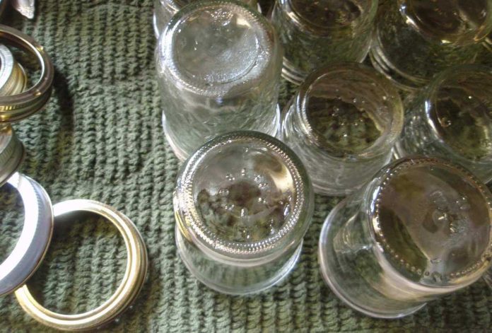 Vasetti per conserve sterilizzati messi ad asciugare a testa in giù su canovaccio assieme ai tappi