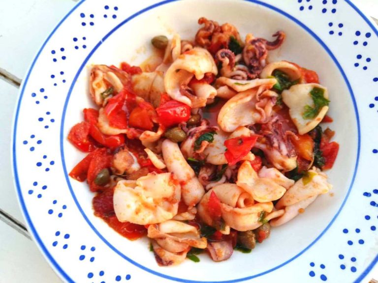 Piatto contenente calamaretti, pomodorini e capperi cucinati in padella