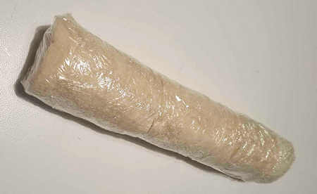 Rotolo di pane per tramezzini farcito avvolto nella pellicola trasparente da cucina