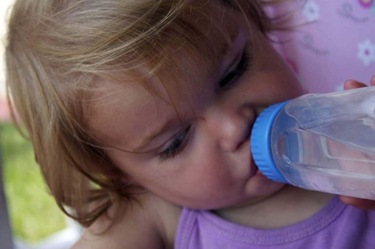 Bambino beve acqua incontaminata da una borraccia pulita