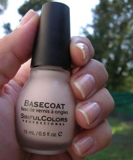 Boccetta contenente base per smalto in mano femminile