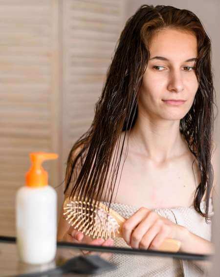 Ragazza distribuisce la crema sui suoi capelli con la spazzola
