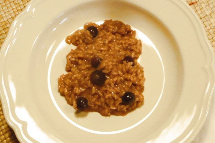 Risotto di una nera decorato con acini interi nel piatto di ceramica