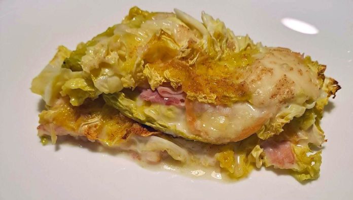 Appetitosa parmigiana di verza con prosciutto e scamorza cotta nel forno Aspetto della parmigiana di verza con prosciutto cotto e scamorza filante