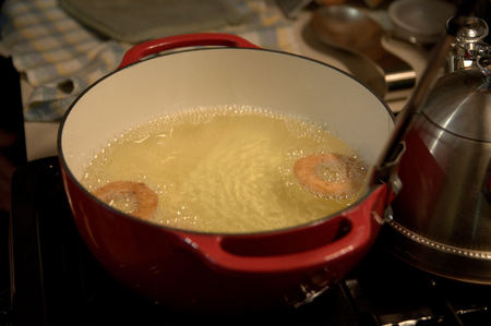Ciambelle dolci friggono in abbondante olio di semi 