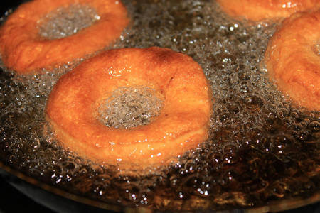Ciambelle dolci friggono in abbondante olio di semi