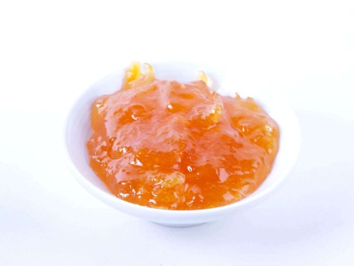 Ciotola di ceramica contenente golosa marmellata di arance e scorzette dell'agurme Marmellata di arance e scorzette in ciotola di ceramica bianca