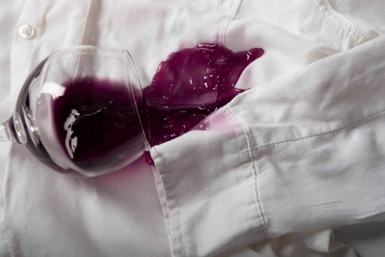 Macchia di vino rosso fresca su camicia bianca da rimuovere prontamente