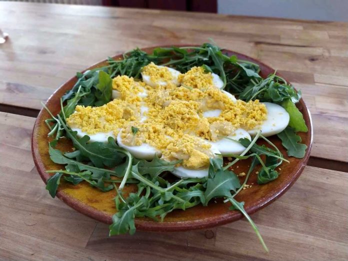 Piatto contenente uova mimosa vegetariane su letto di rucola Uova mimosa senza tonno vegetariane decorate con rucola su piatto di portata