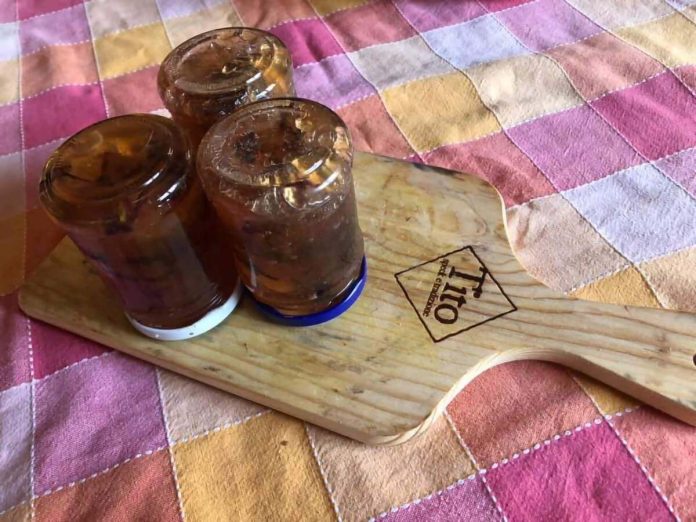 Barattoli a testa in giù contenenti confettura di violette e mele della nonna Confettura di violette e mele della nonna invasata in barattoli capovolti.