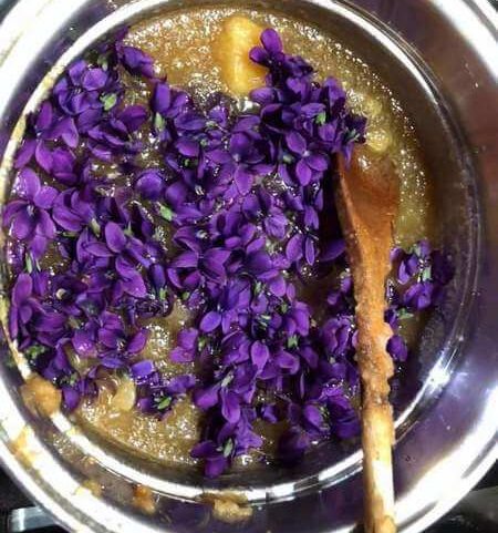 Confettura di violette e mele in cottura con cucchiaio di legno