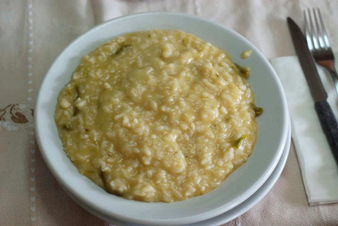 Piatto contenente cremoso e gustoso risotto con bruscandoli alla veneziana Risotto con bruscandoli alla veneziana nel piatto