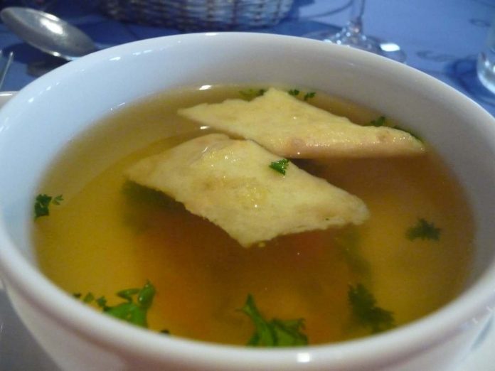 Tazza contenente brodo vegetale fatto in casa con crostini