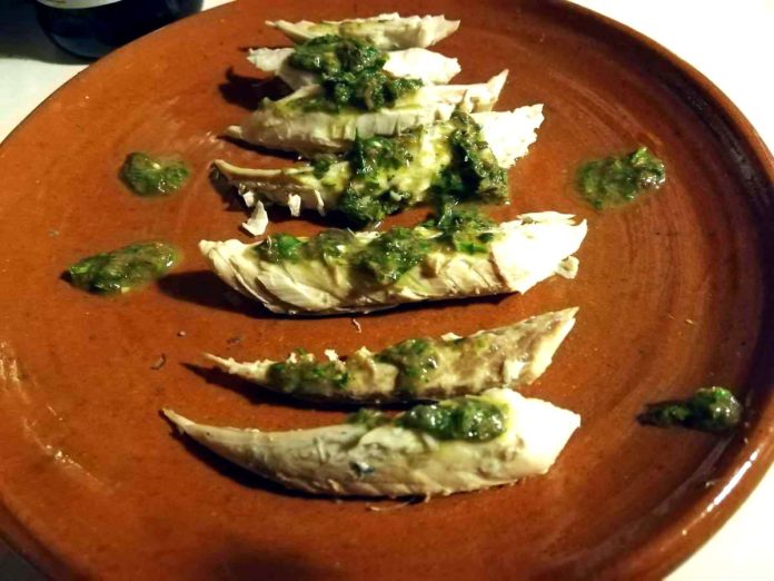 Filetti di barracuda con salsa di limone e prezzemolo su piatto marrone