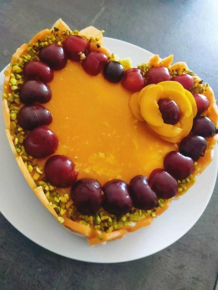 Decorazione di frutta e granella di pistacchi sulla cheesecake al melone priva di mascarpone Cheesecake al melone senza mascarpone decorata con frutta e granella di pistacchi