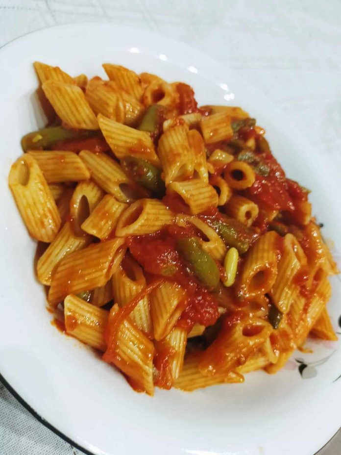 Invitante e gustosa pasta condita con fagiolini, pomodoro e cacioricotta Aspetto delle mezze penne con fagiolini, pomodoro e cacioricotta alla pugliese