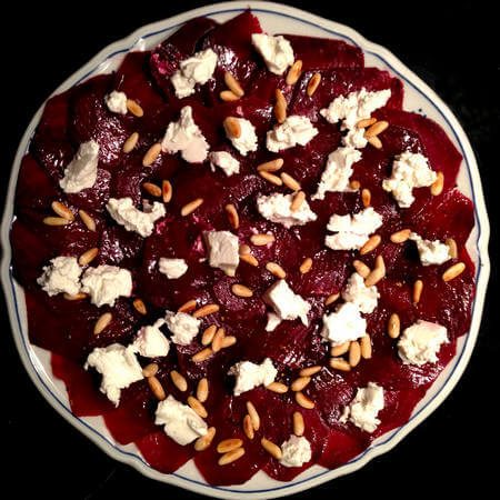 Insalata di barbabietole, formaggio caprino e pinoli in piatto di portata tondo