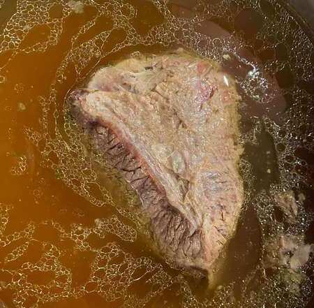 Pezzo di manzo immerso nel brodo di carne bollente 