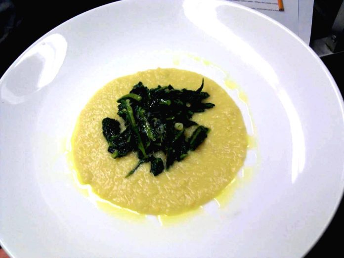 Piatto contenente appetitosa e salutare crema di ceci e cicoria Crema ci ceci e cicoria servita nel piatto di ceramica bianca