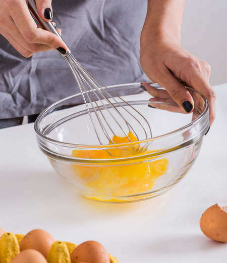 Donna sbatte con la frusta un uovo nella ciotola