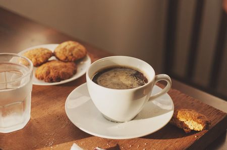 Tazzina di caffè con accanto biscotti sul piattino