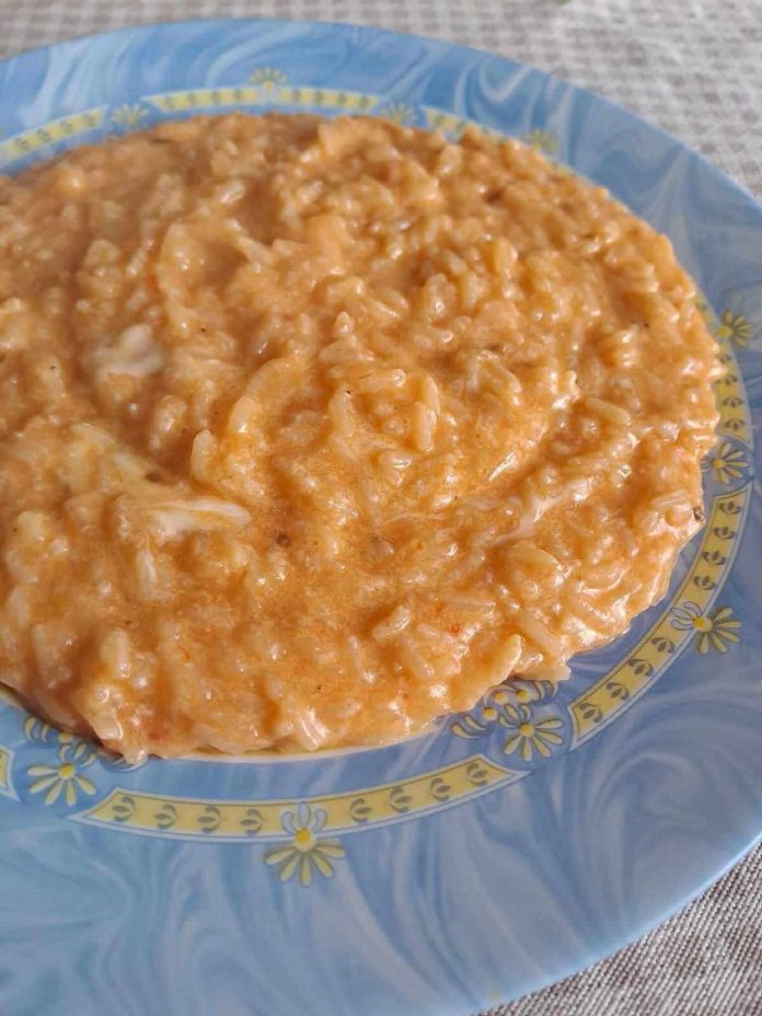 Cremoso e invitante risotto alla pizzaiola servito in un piatto elegante Risotto alla pizzaiola servito in piatto azzurro con decori dorati