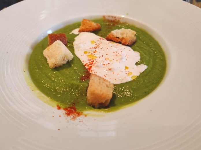 Aspetto invitante della vellutata di piselli e lattuga con burrata servita con decorazione di crostini e paprika in polvere Vellutata di piselli e lattuga con burrata decorata con crostini e paprika