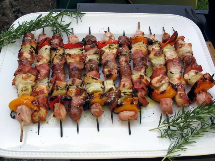 Gustosi e allegriPiatto di portata con sopra gustosi spiedini misti aromatizzati con paprika affumicata Spiedini di carni miste alla paprika su piatto di portata rettangolare