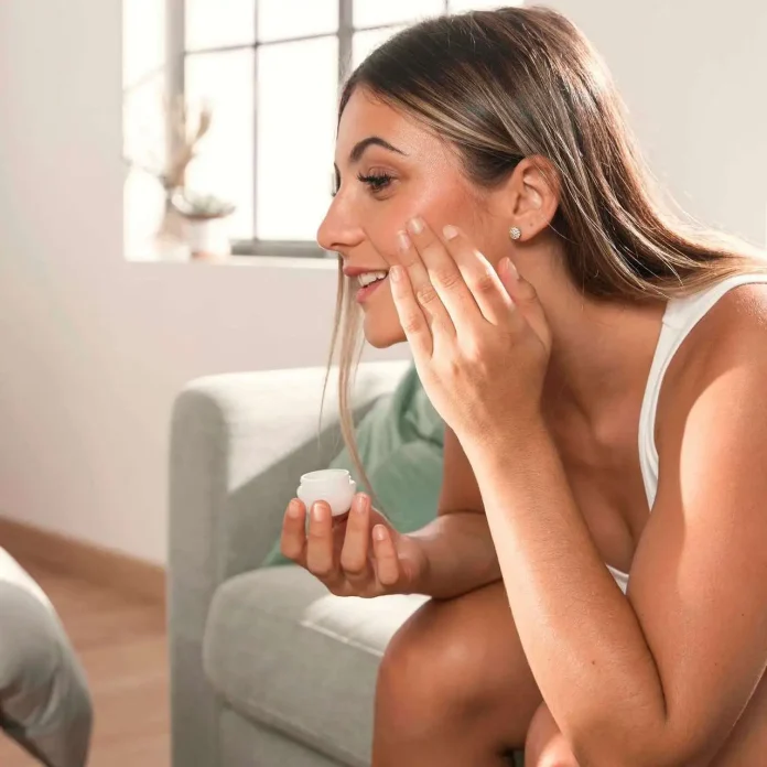 Applicare la crema alla vitamina C sulla pelle abbronzata combatte i danni provocati dai raggi UV Donna si applica crema alla vitamina C sul viso abbronzato per ripararlo dai danni causati dal sole
