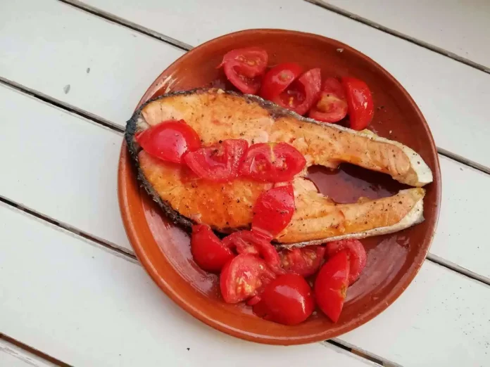 Salmone cucinato in padella con pomodorini in piatto di terracotta