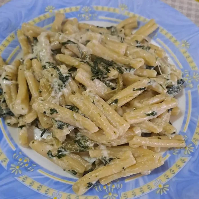 Invitante pasta con acciughe, cicoria e stracciatella servita in un piatto elegante Pasta con acciughe, cicoria a stracciatella in piatto elegante con decori d'oro