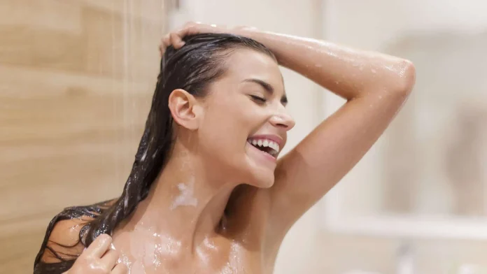 Ragazza sorridente si rilassa sotto alla doccia