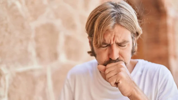 Giovane uomo ha un attacco di tosse provocato da catarro in gola Giovane uomo tossisce in strada a causa del catarro in gola